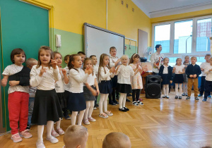 Zdjęcie przedstawia dzieci, które śpiewają dla pracowników