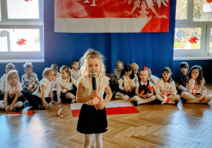 Zdjęcie przedstawia dziewczynkę recytującą wiersz