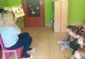 Zdjęcie przedstawia panią bibliotekarkę, która czyta książkę