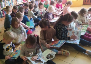 Zdjęcie przedstawia dzieci, które oglądają wybrane książki