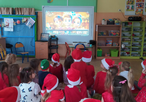 Zdjęcie przedstawia dzieci, które oglądają film edukacyjny o Mikołaju
