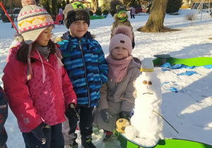 Zdjęcie przedstawia dzieci i bałwanka