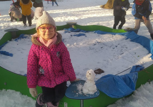 Zdjęcie przedstawia dziewczynkę i jej bałwanka