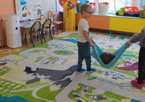 Zdjęcie przedstawia dzieci podczas zabawy ruchowej Przenieś bryłę lodu