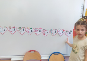 Zdjęcie przedstawia dziewczynkę, która dopasowuje ilość serc do cyfry