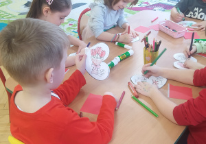 Zdjęcie przedstawia dzieci, które ozdabiają Walentynkę dla rodziców