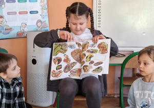 Zdjęcie przedstawia dziewczynkę, która prezentuje swoją książkę