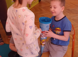 zdjecie przedstawia chlopca czestujacego cukierkami